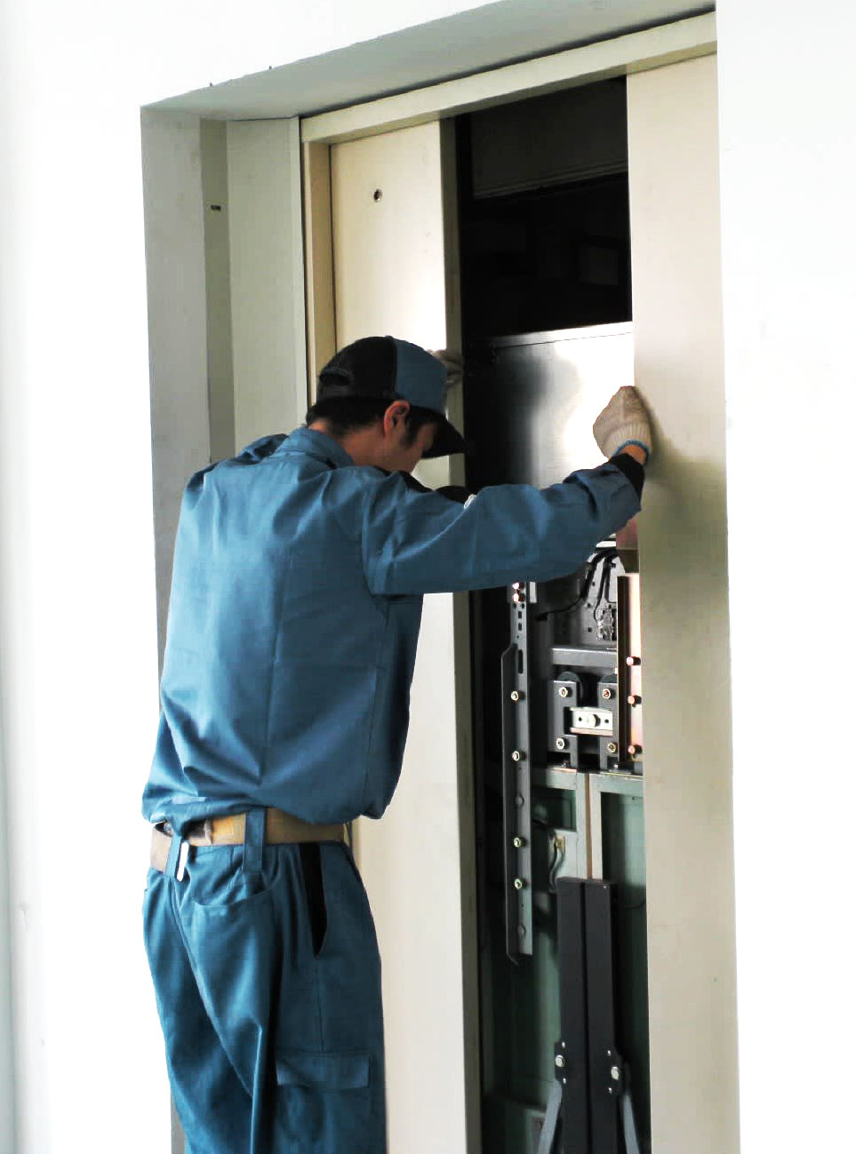 Técnico da JND Elevadores instalando componentes de porta de elevador